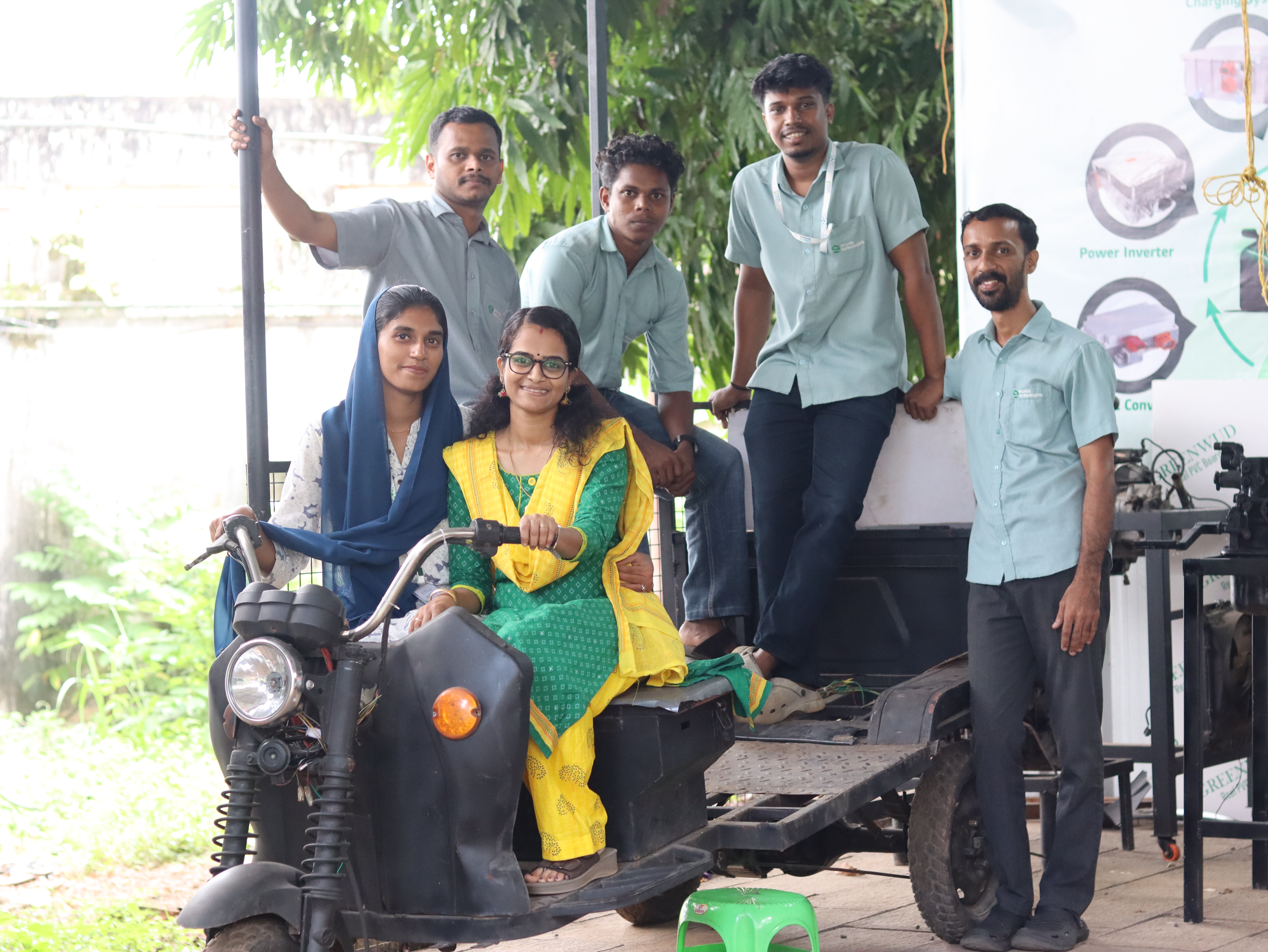 Students posing with an EV training vehicle at Eroots Technologies.