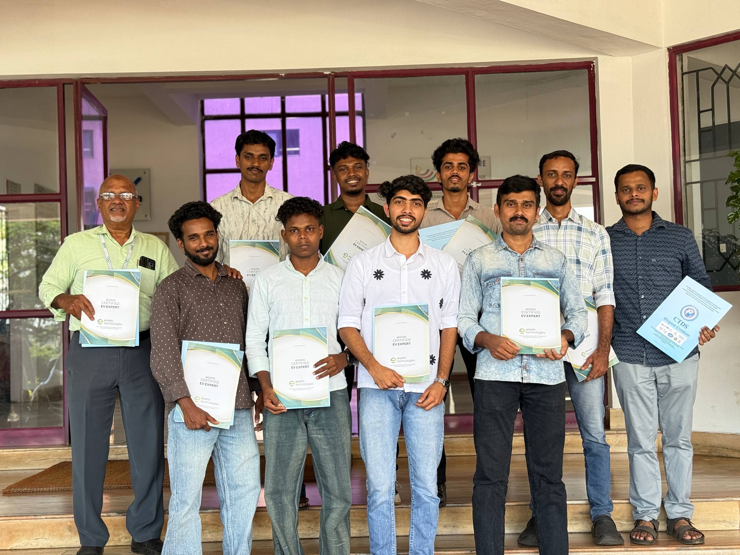 Students posing with EV expert certificates outside the venue.