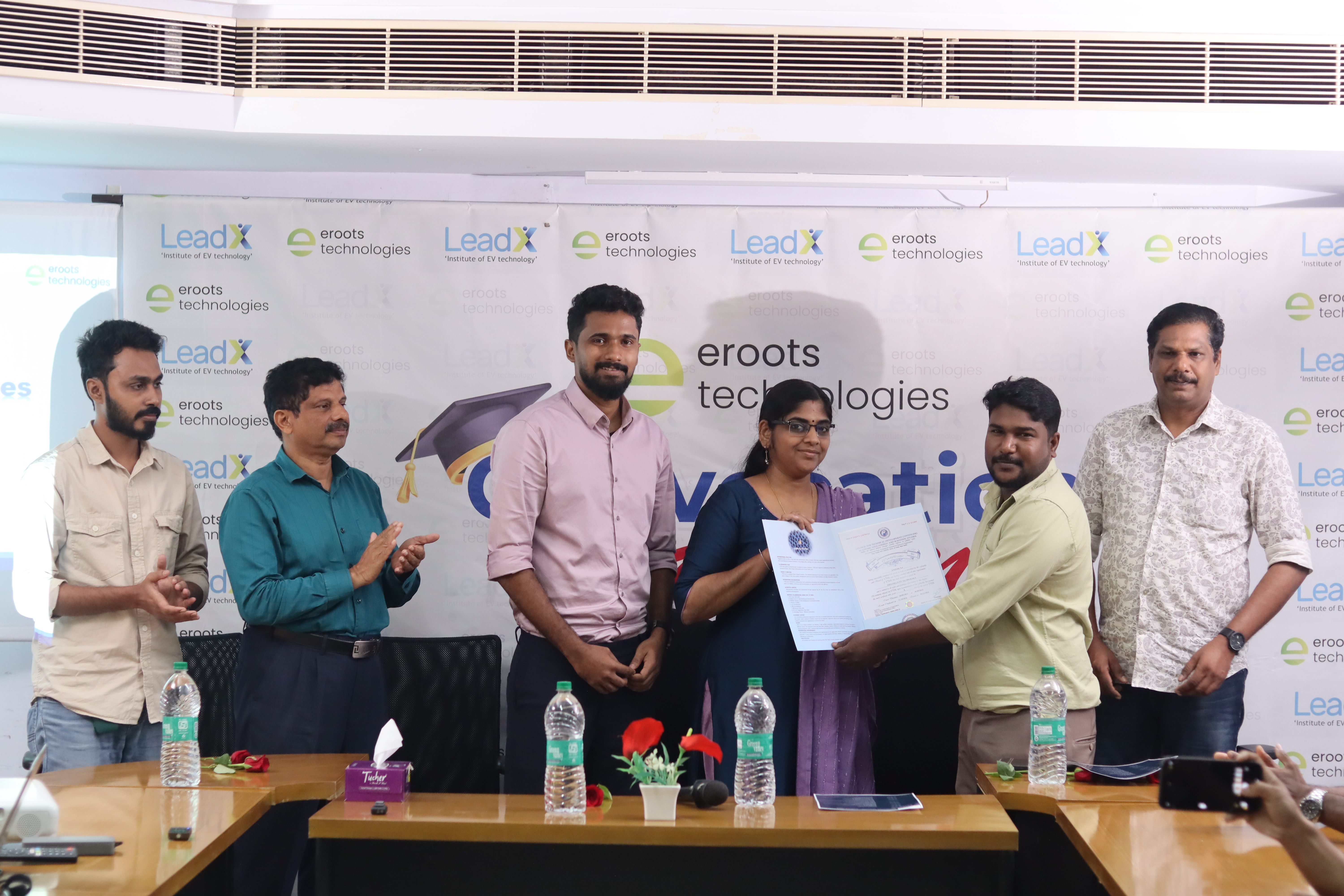 Certificate handover to student at Eroots Technologies event.
