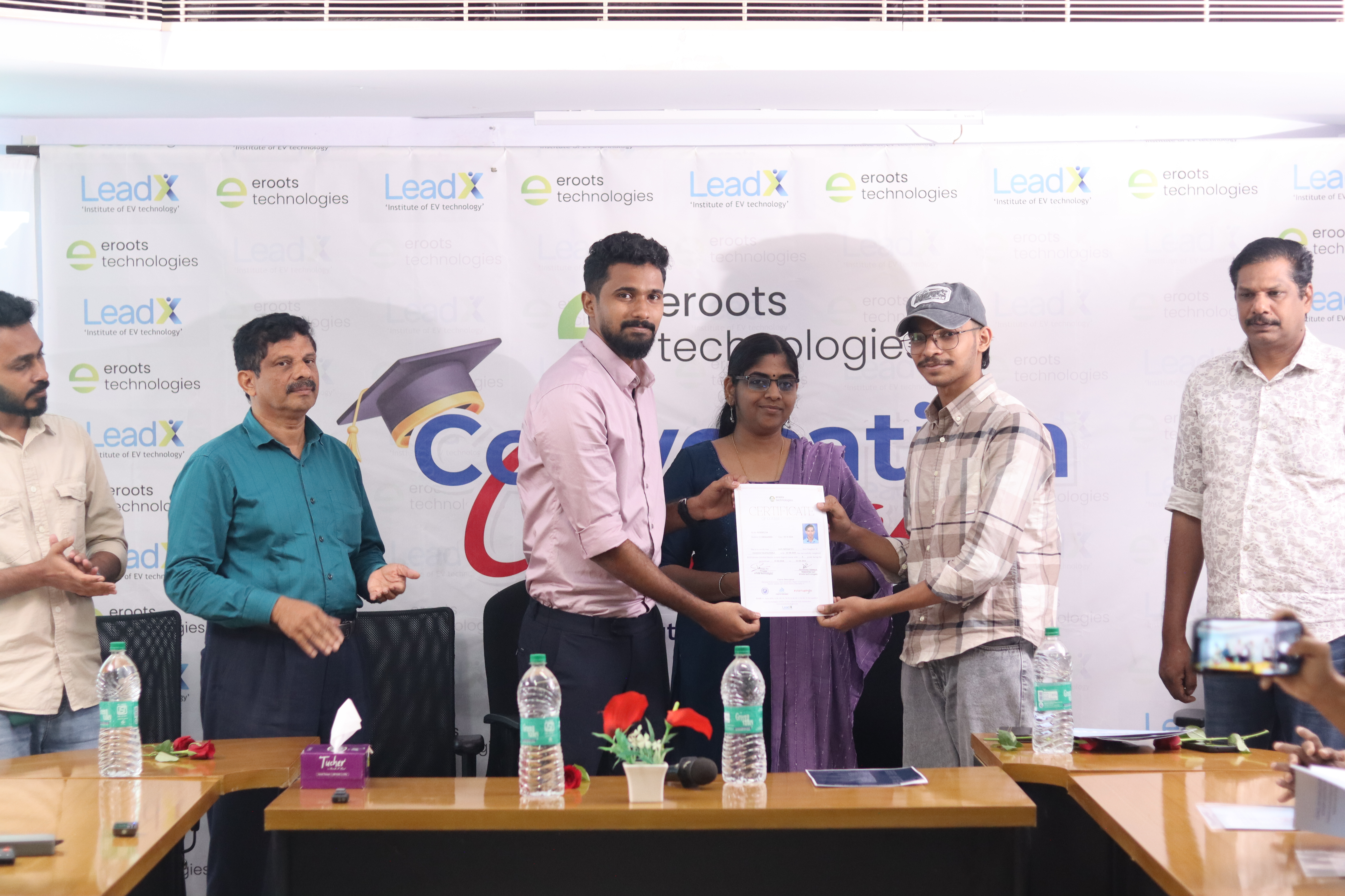 Student receiving certificate during Eroots Technologies event.