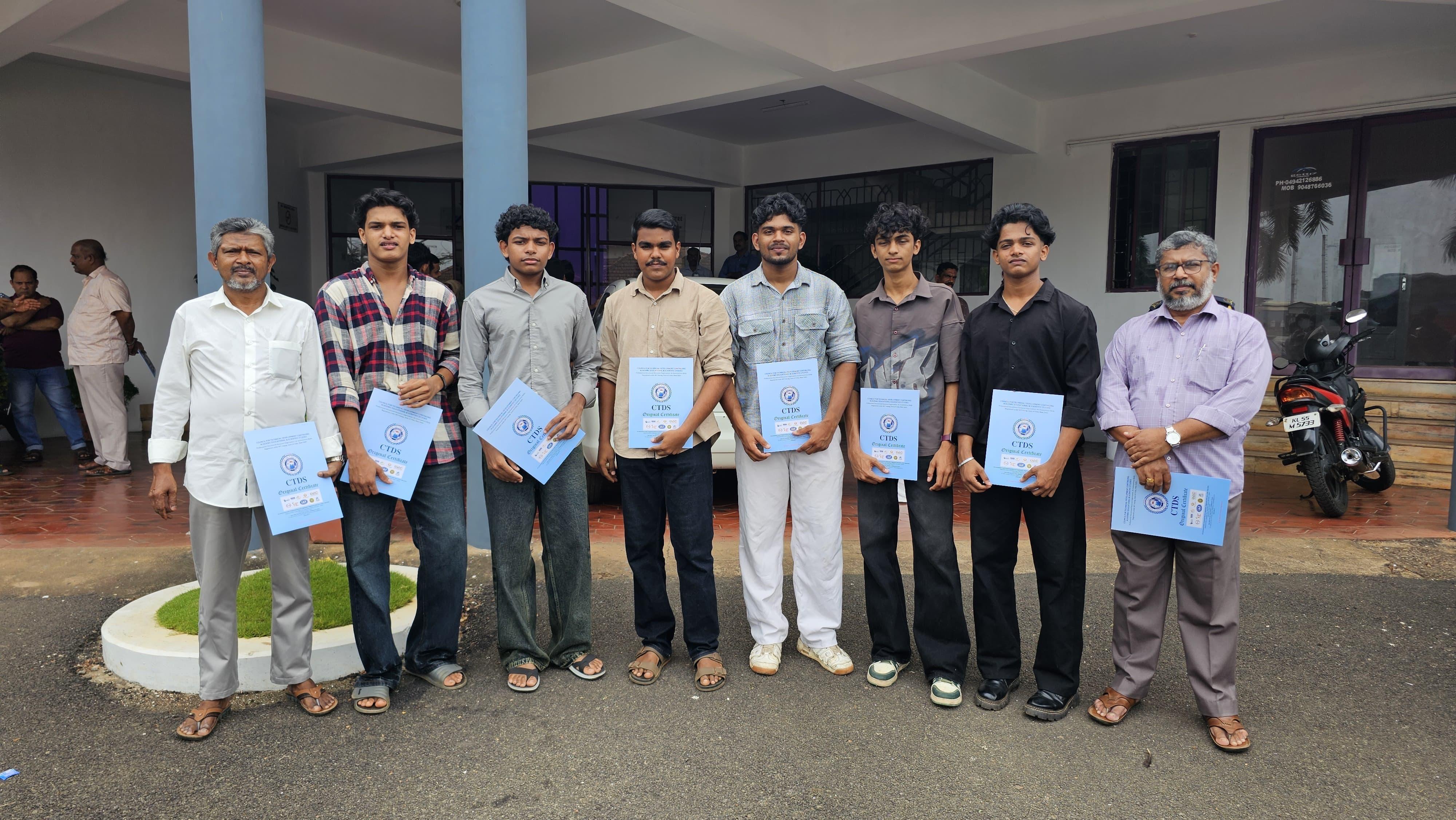 Students and faculty group photo with certificates outside the venue.