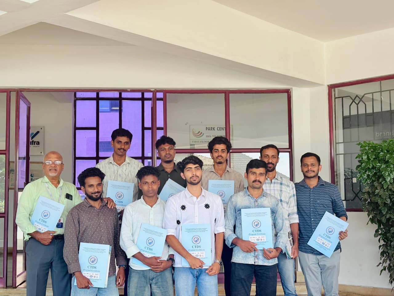 Certificate group photo in front of the building entrance.